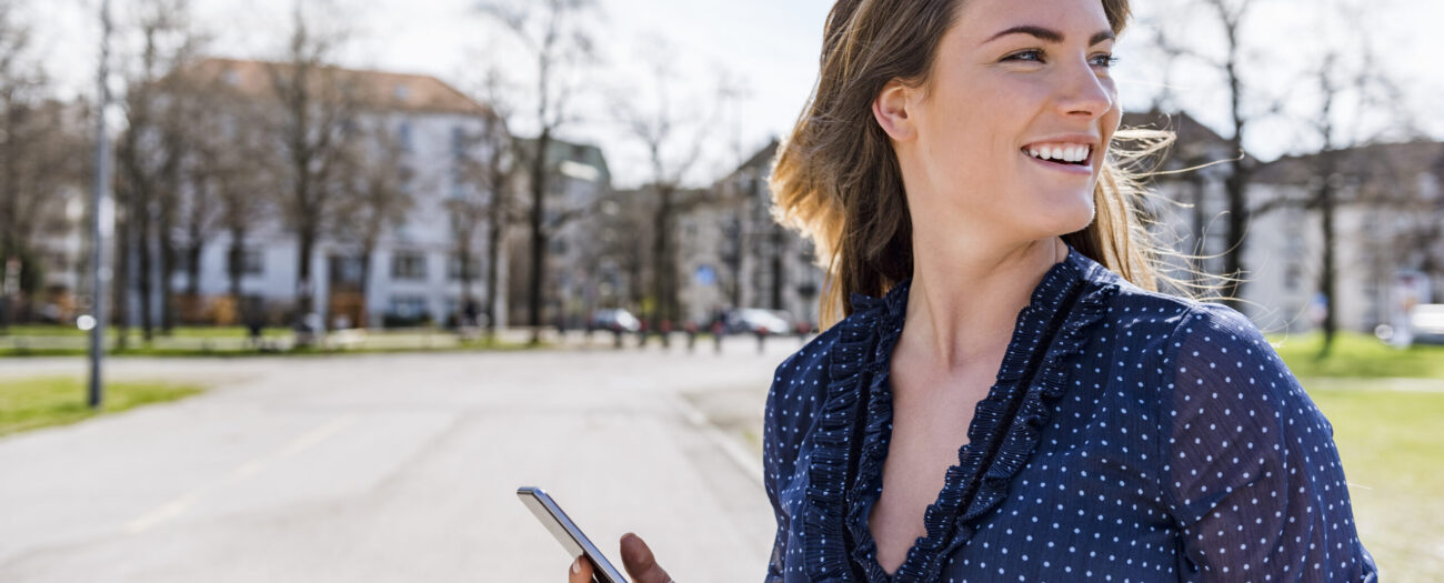woman smiling while holding her mobile phone on her self guided tour