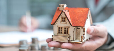 property manager holds a model house in his hand as he writes
