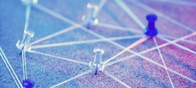 thumbtacks on a board interconnected with strings to create a network of connections between them