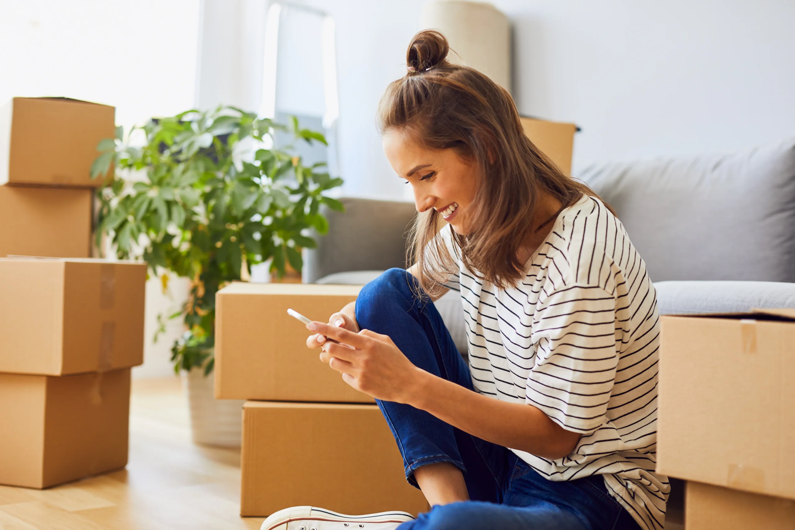 Renter smiling at phone while moving into new apartment
